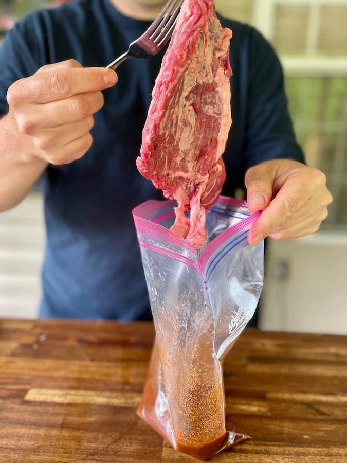 adding skirt steak to a bag of homemade steak fajita marinade