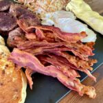 bacon on a cutting board with other griddle breakfast foods