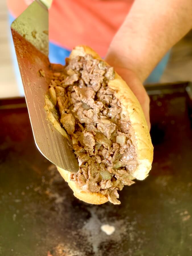 adding cheesesteak to a roll