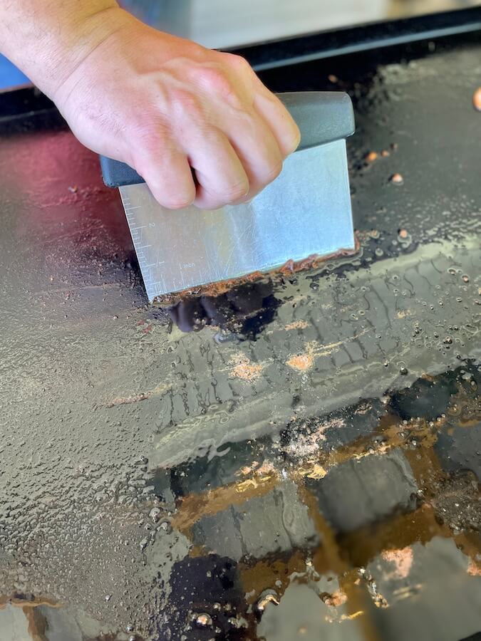 cleaning blackstone griddle with a bench scraper