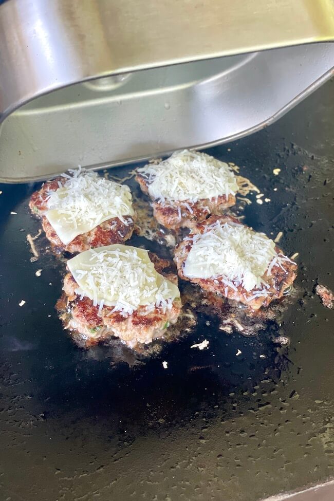 smashed meatballs cooking on a griddle