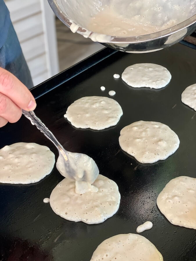 spooning pancake batter on the griddle