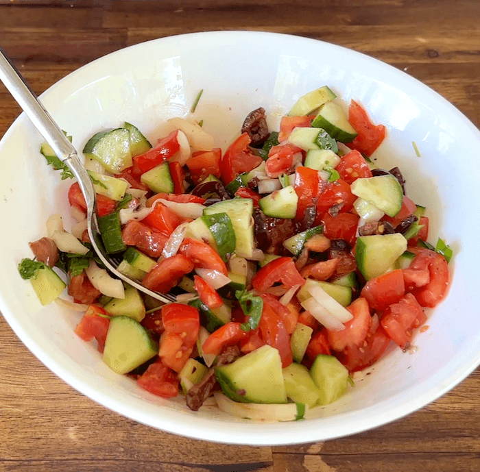 chopped tomato, cucumber, onion, and kalamata olives in a bowl