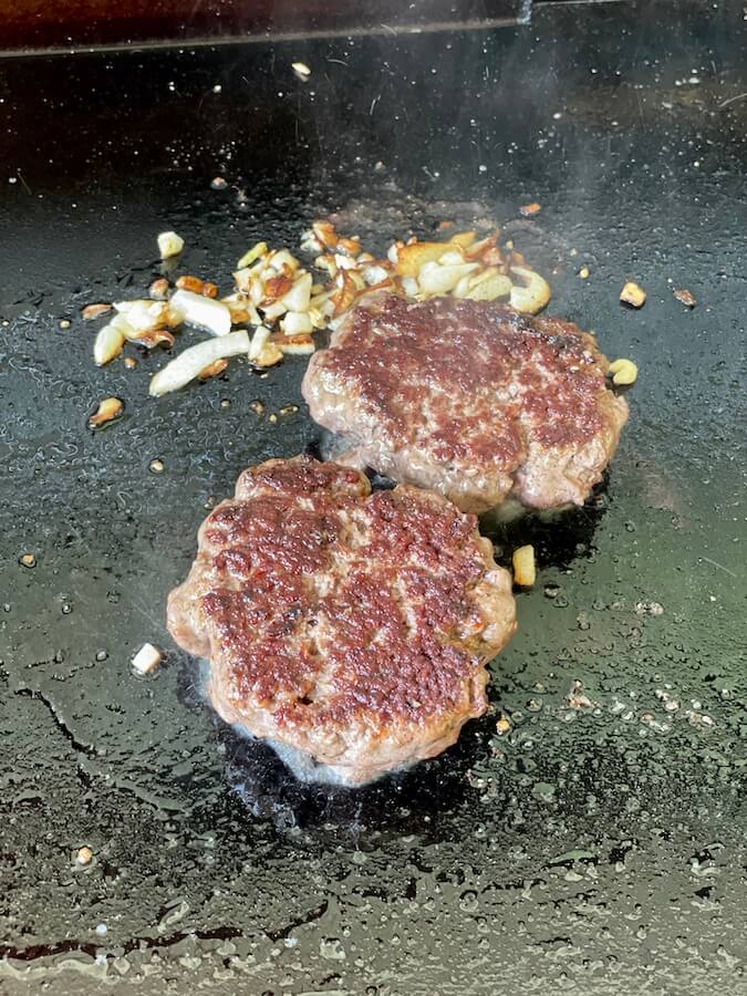 hamburger patties cooking on a griddle