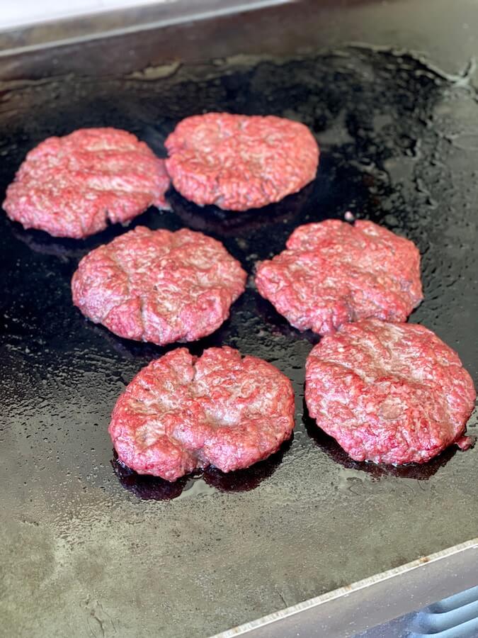 smoked beef patties searing on a blackstone griddle