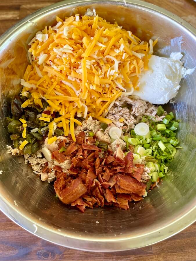 shredded cheese, cream cheese, jalapenos, bacon, and shredded chicken in a bowl