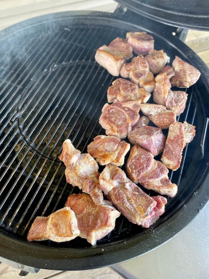 cut pork butt smoking on a grill