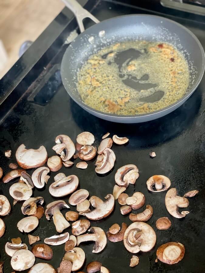 mushrooms and a skillet of butter and garlic on the griddle