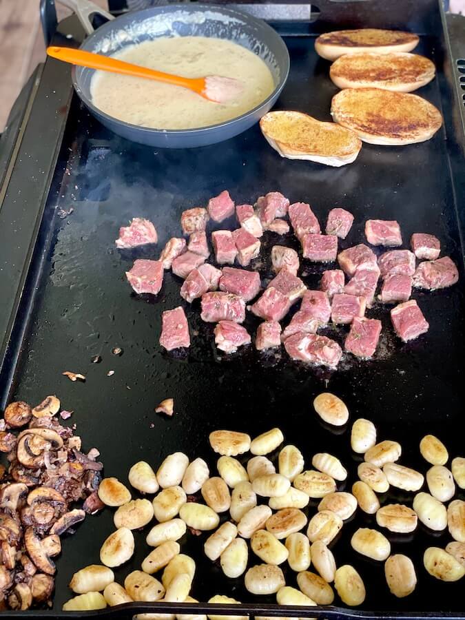 making steak bites and gnocchi on blackstone grill