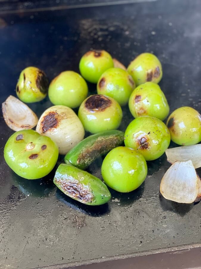 grilling tomatillos, onions, and jalapenos on the flat top grill