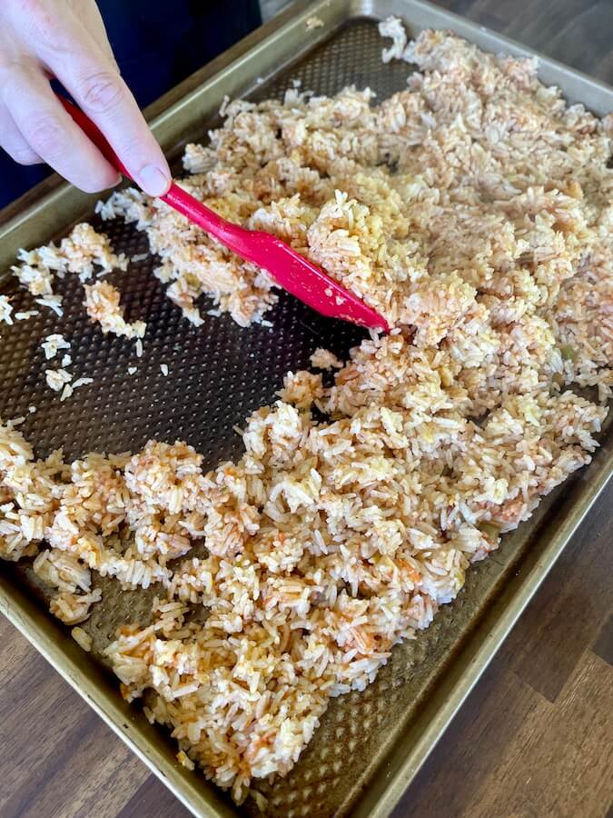 spreading cooked Mexican rice on a sheet tray to cool