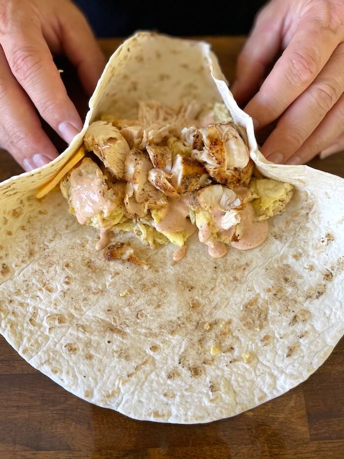 wrapping chicken breakfast burrito in a tortilla
