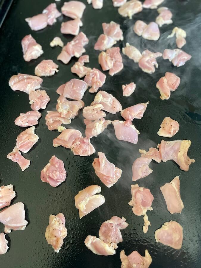 cut chicken cooking on a Blackstone griddle