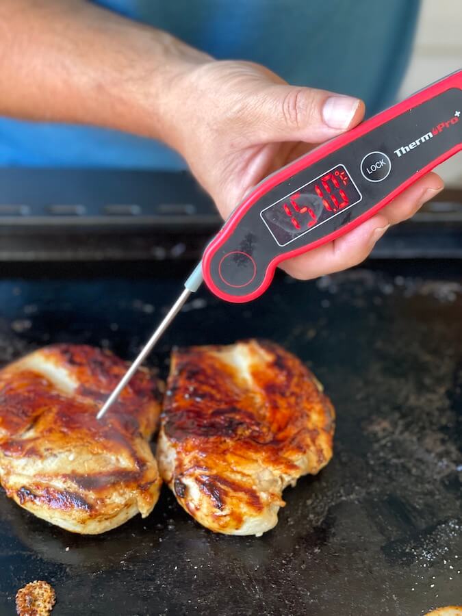 checking internal temperature of grilled chicken on the blackstone