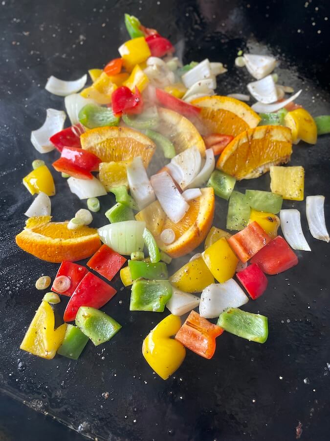 bell peppers, onions, and orange slices on a Blackstone griddle