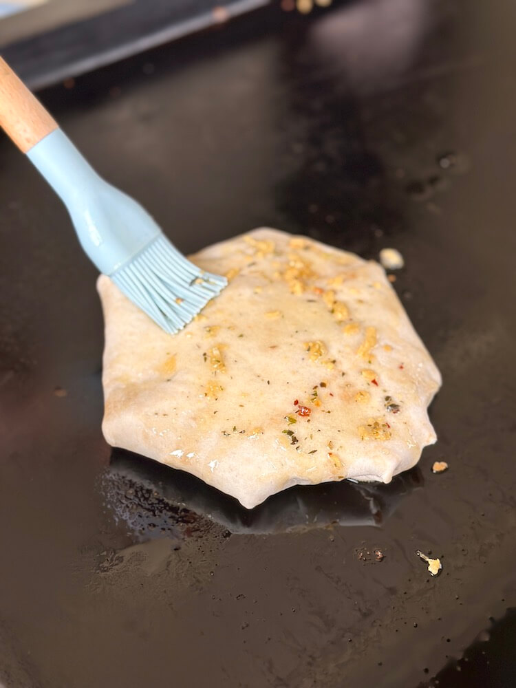 brushing melted butter and garlic on the outside of a pizza tortilla wrap