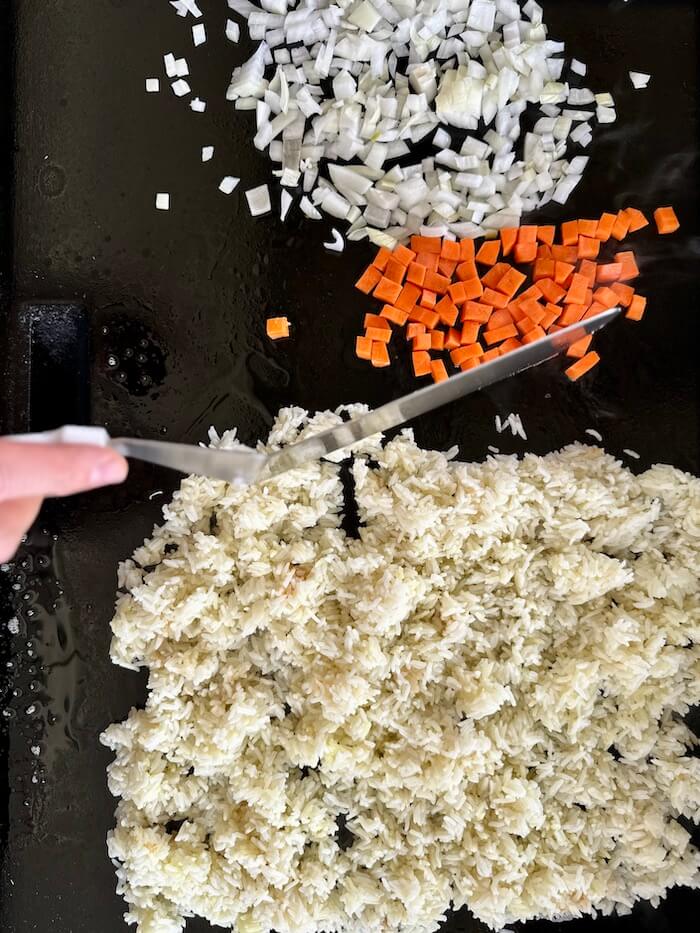 white rice, carrots, and onions on a griddle