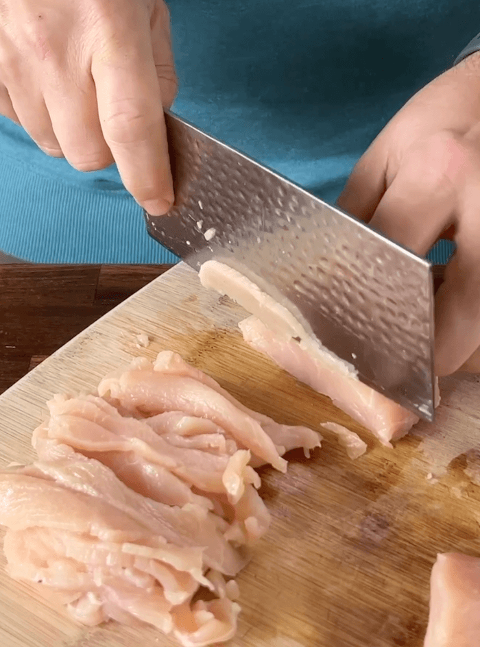 slicing chicken breast into thin strips
