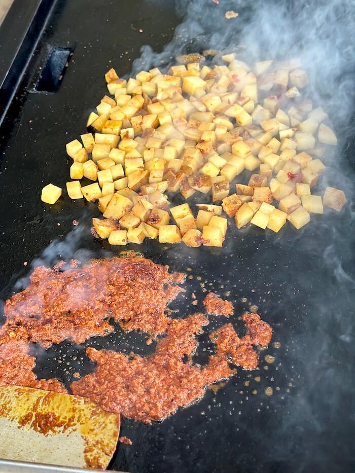 Mexican potatoes and chorizo cooking on a griddle