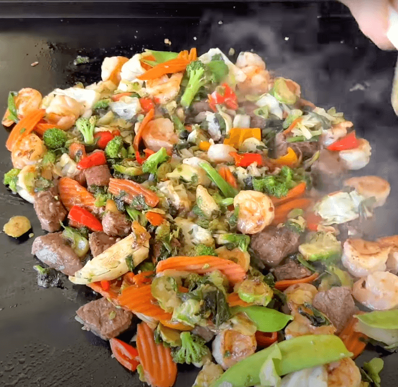 shrimp and steak stir fry cooking on a Blackstone
