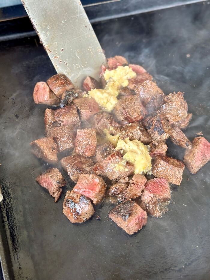 bite-sized cubes of steak on a griddle with garlic butter