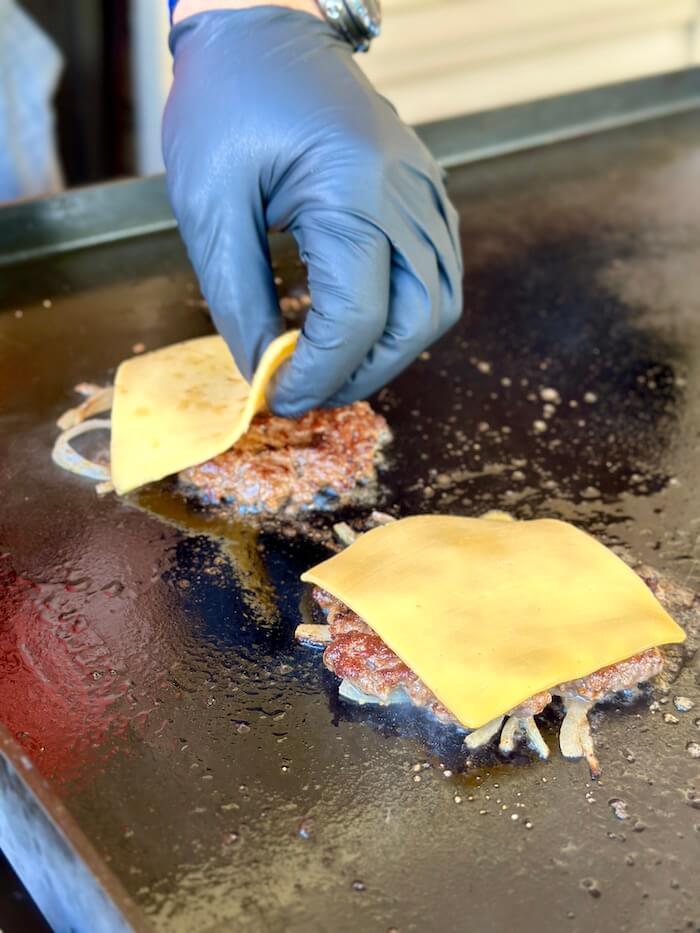 putting cheese on butter smash burgers