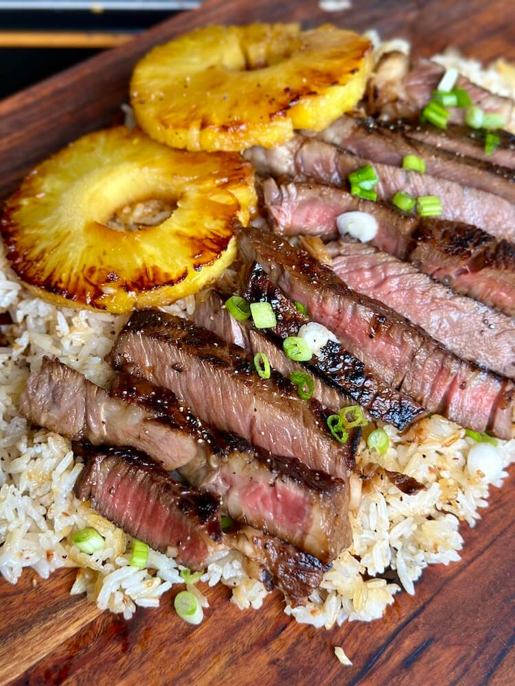 sliced Hawaiian ribeye steak served over white rice with grilled pineapple rings