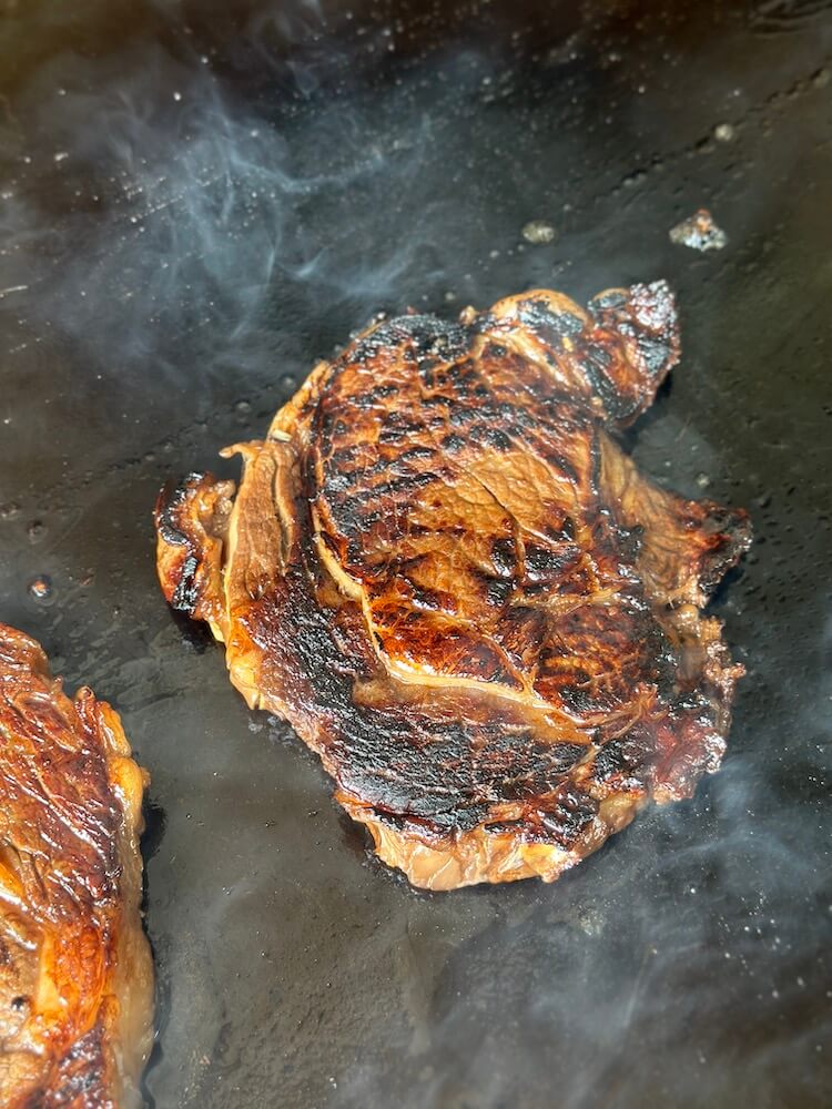 Hawaiian ribeye with a good sear cooking on a griddle