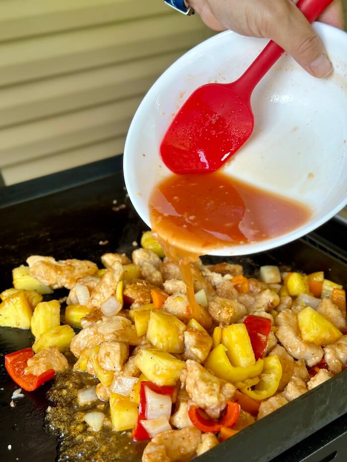 pouring sweet and sour sauce over crispy chicken