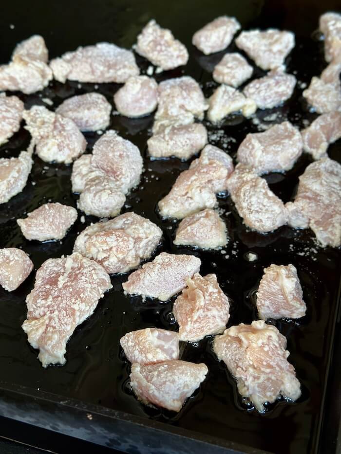 cornstarch coated chicken cooking on a griddle