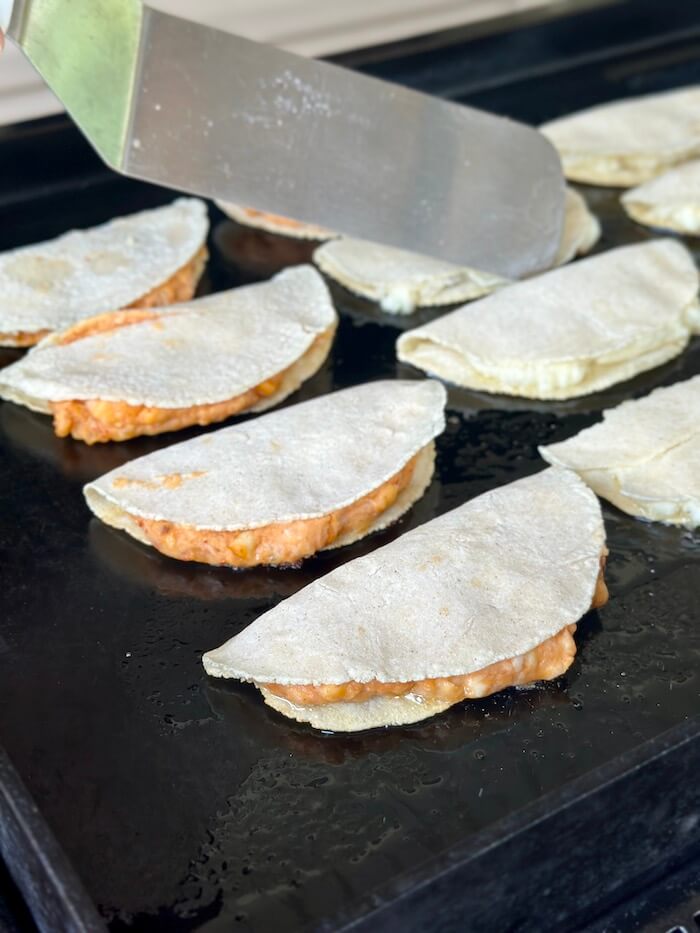 frying potato tacos on a griddle