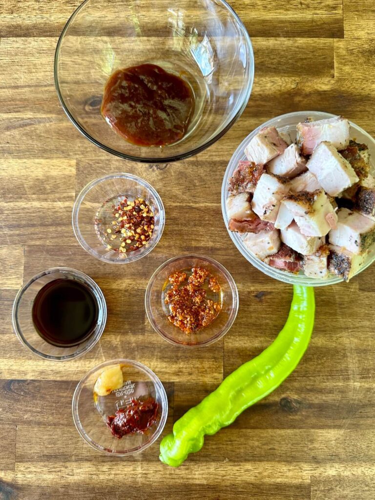 cubed pork belly, Asian sauces, and spices on a cutting board