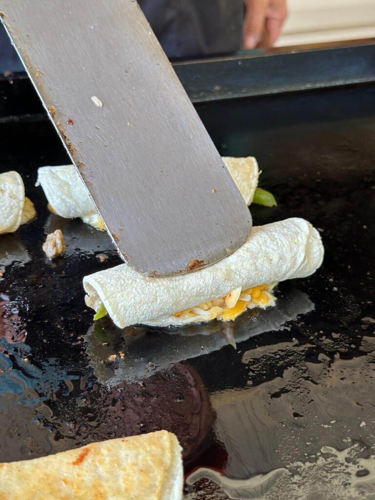 using a spatula to make Philly cheesesteak taquitos