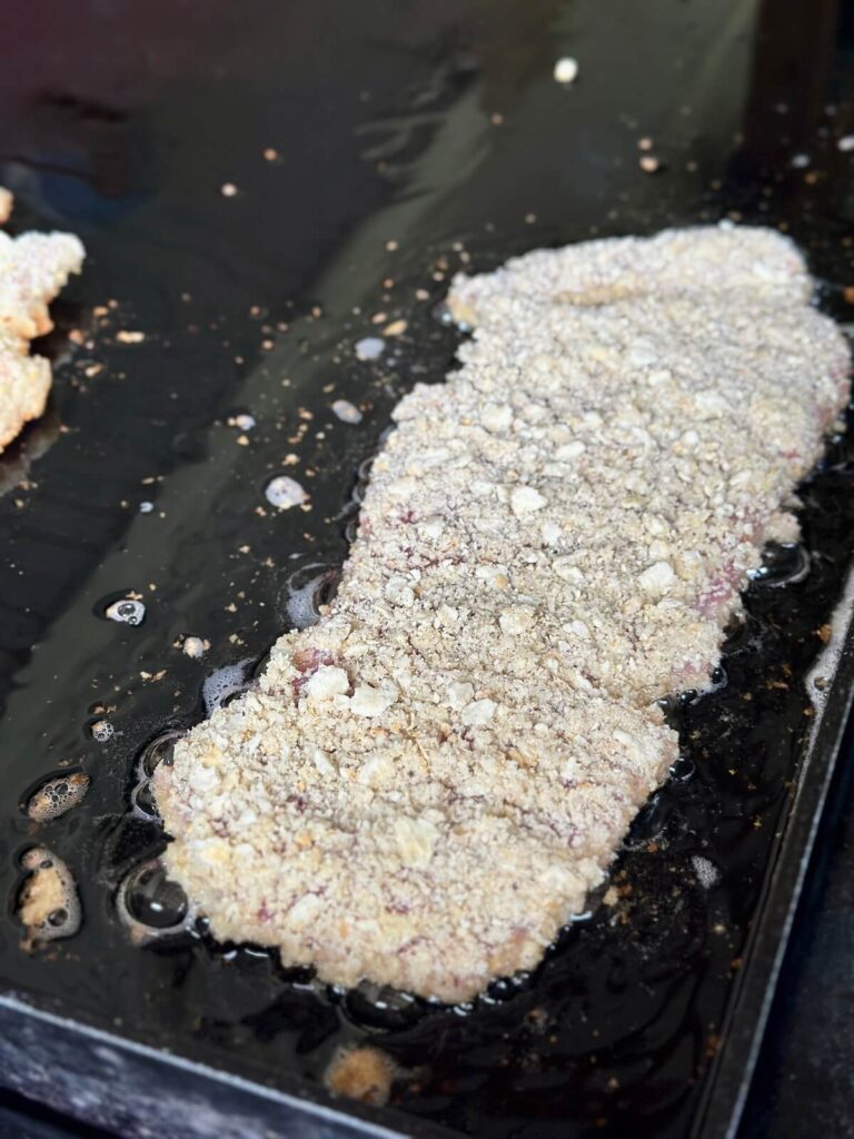 frying a piece of breaded pork tenderloin