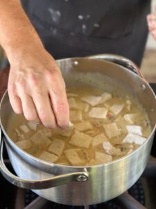 placing rolled dumplings on turkey soup mix