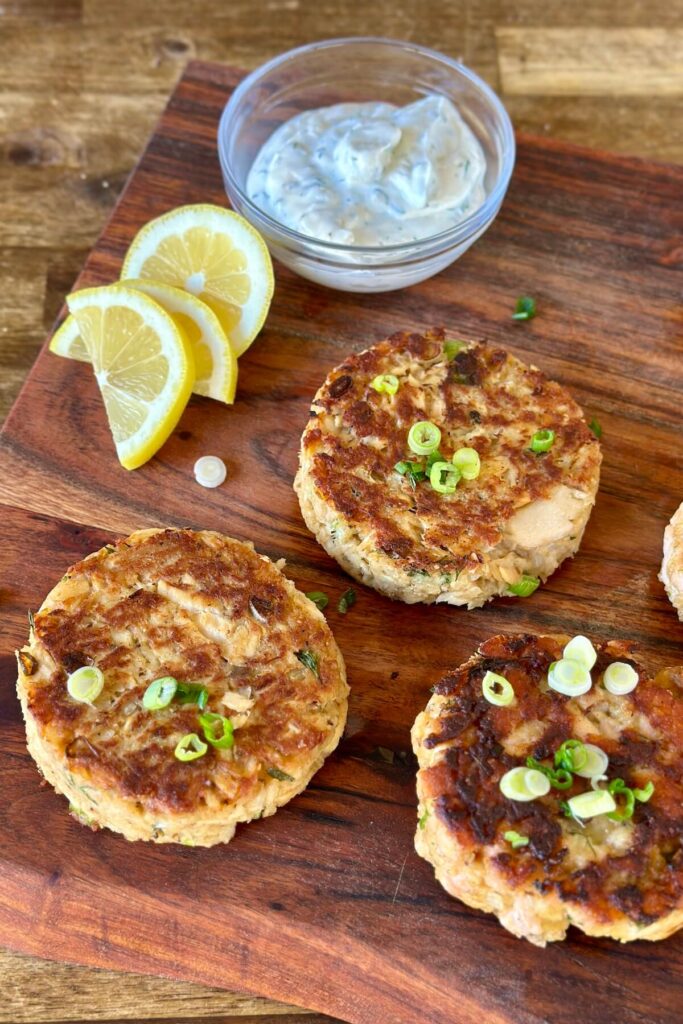 salmon patties with yogurt dill sauce and lemon wedges