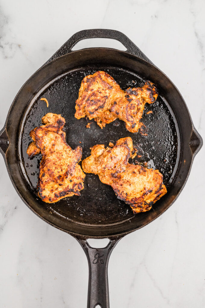 cooking Mexican marinated chicken thighs in a cast iron skillet