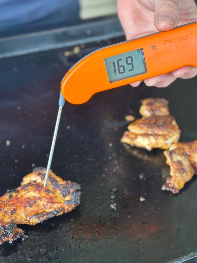 using an instant read meat thermometer to check the internal temp of chicken thighs