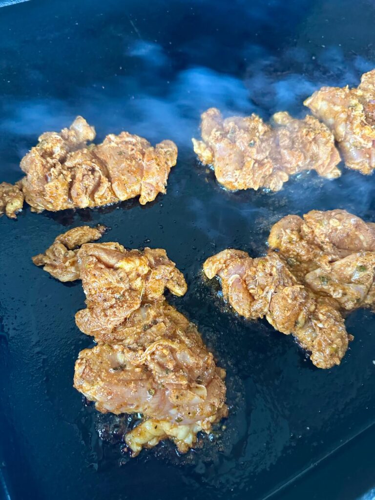 cooking marinated boneless skinless chicken thighs on a griddle