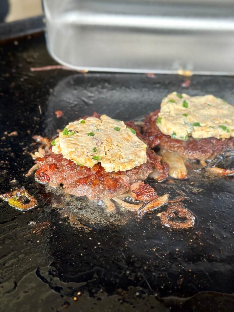 cooking smash burgers with jalapeno cream cheese mixture on top