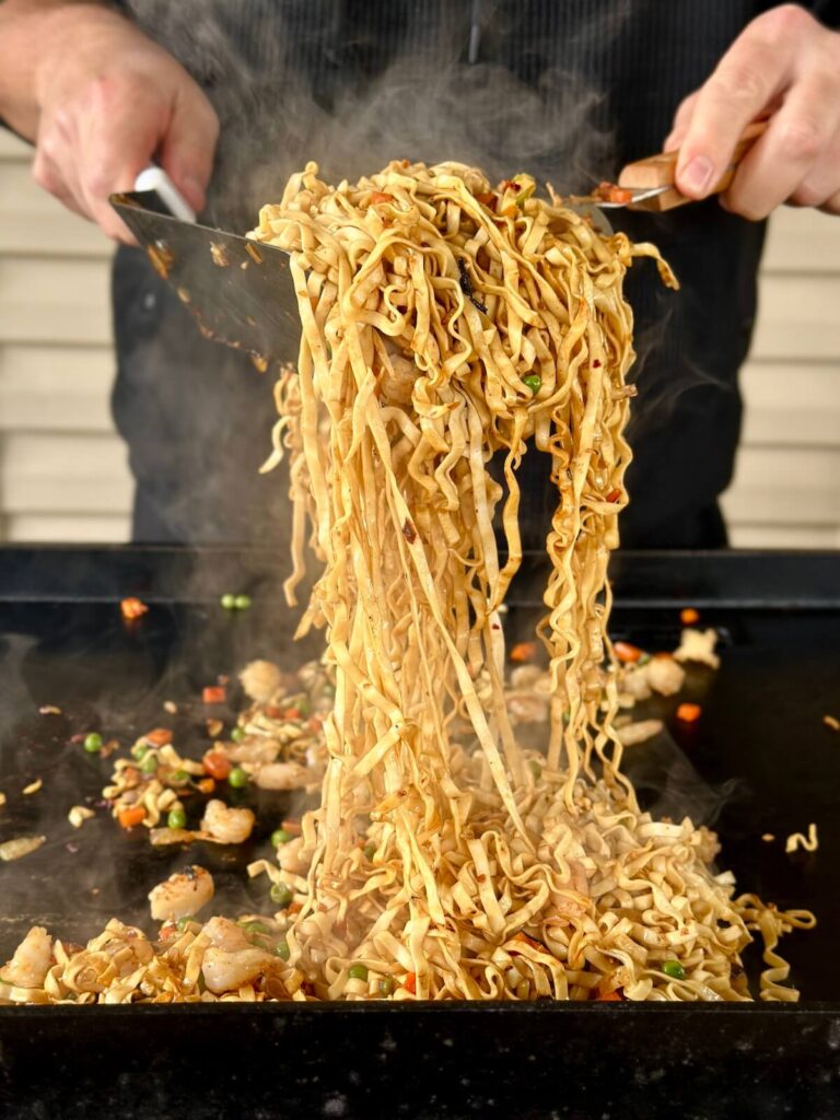 making shrimp and noodle stir fry on a griddle