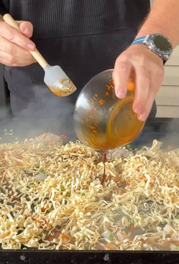 pouring sauce on stir fry noodles