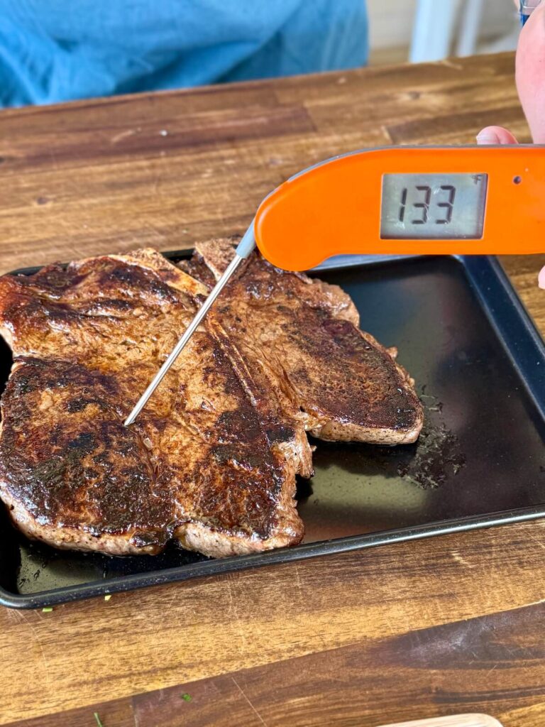 using an instant read meat thermometer to check temperature of a steak