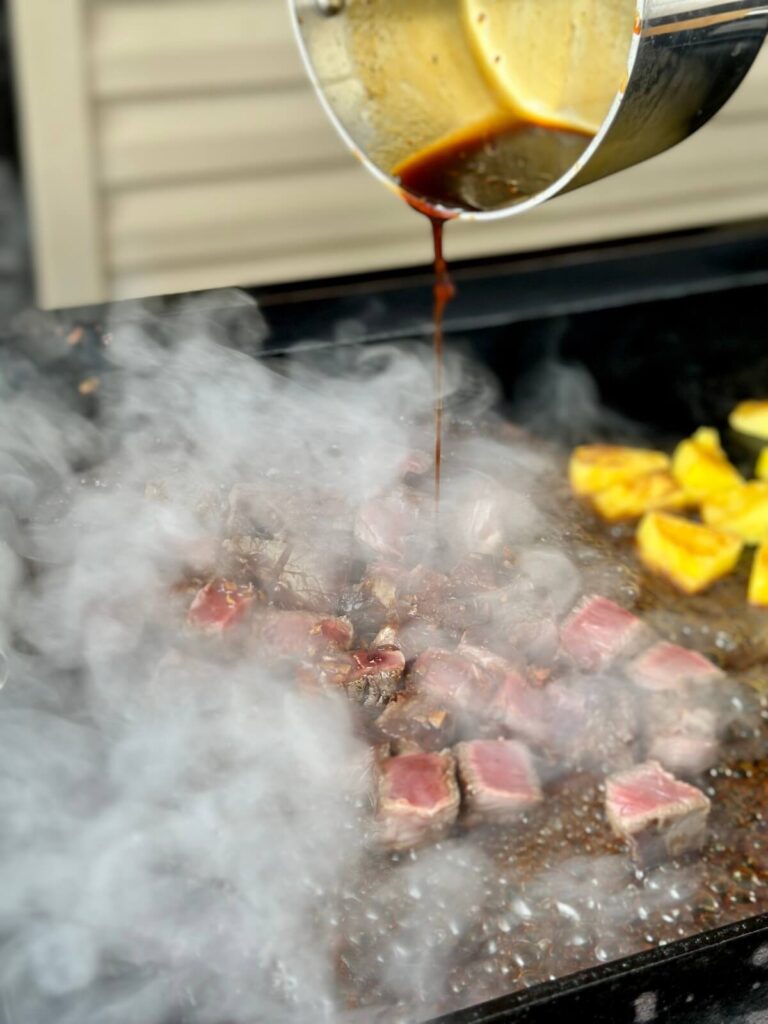 pouring teriyaki sauce over steak bites