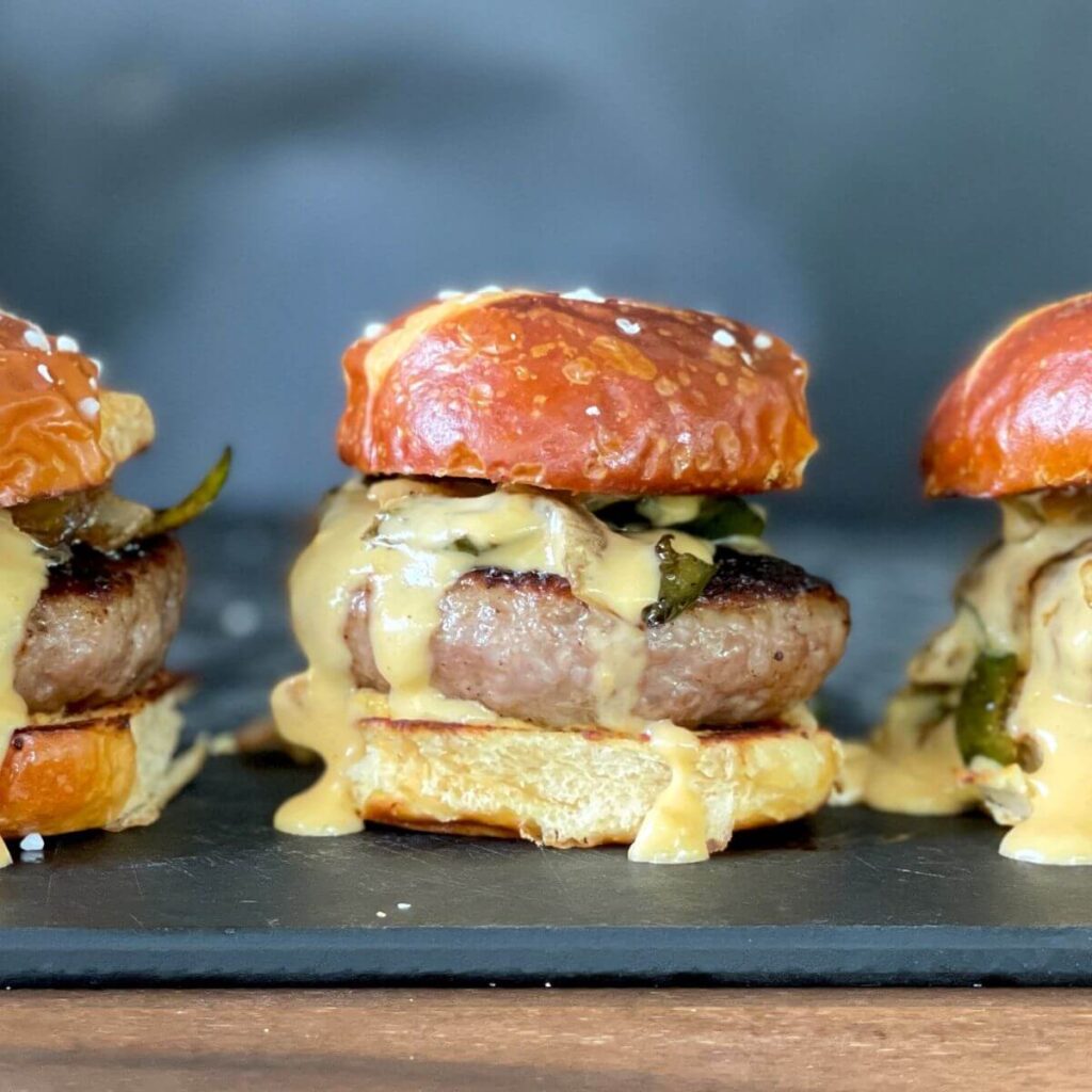 brat burger sliders on pretzel buns with beer cheese sauce