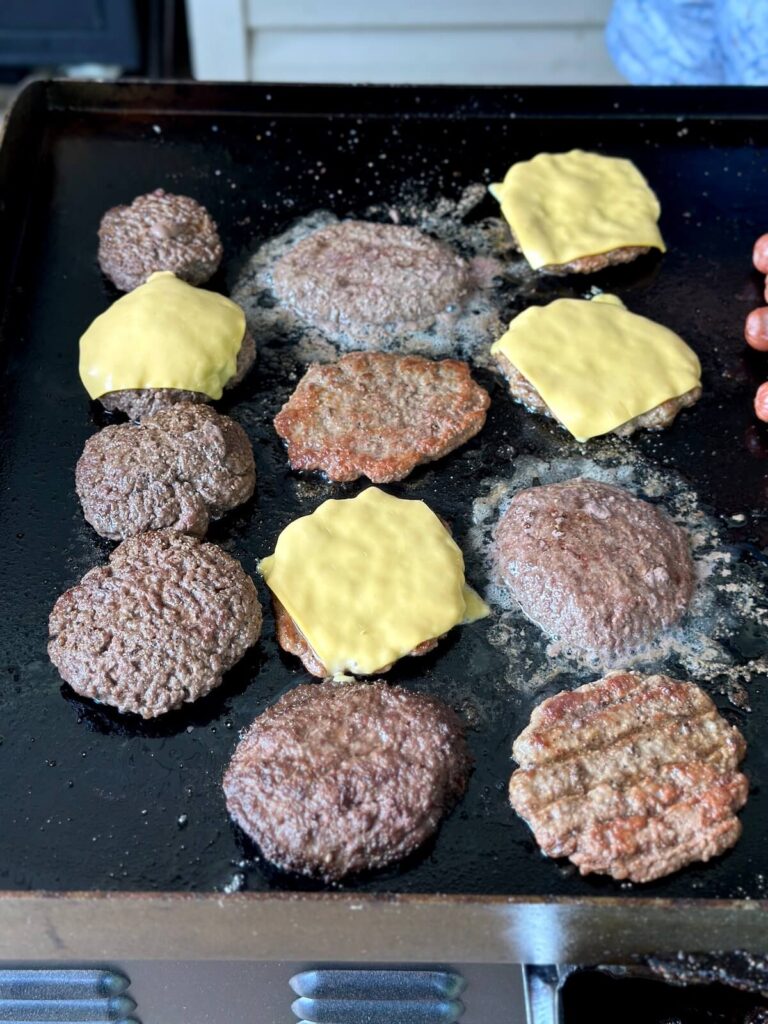 cooking a lot of burgers on a griddle at once