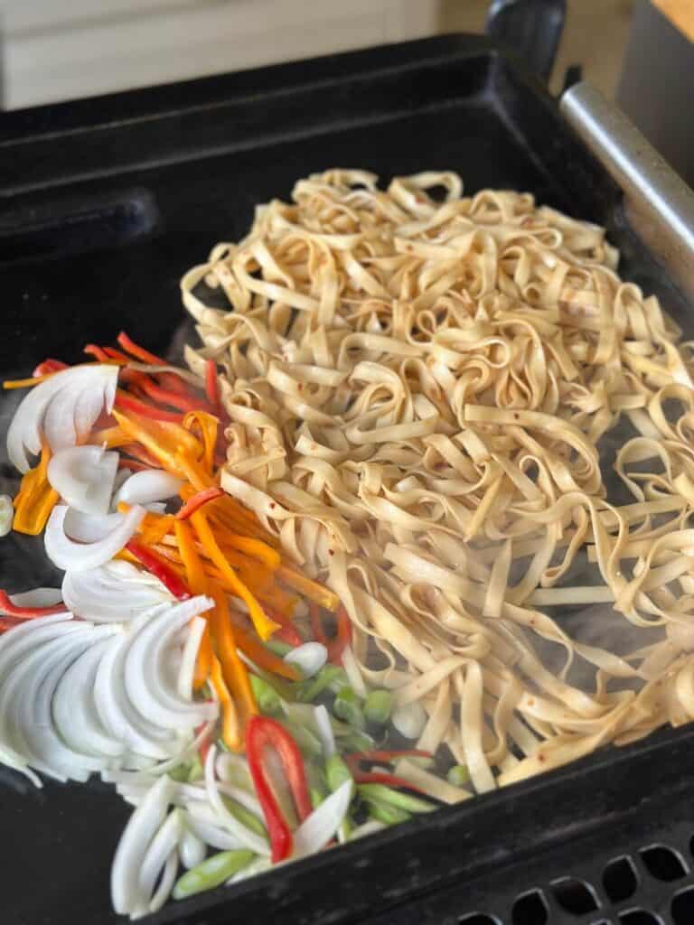 cooking Chinese lo mein noodles on the griddle
