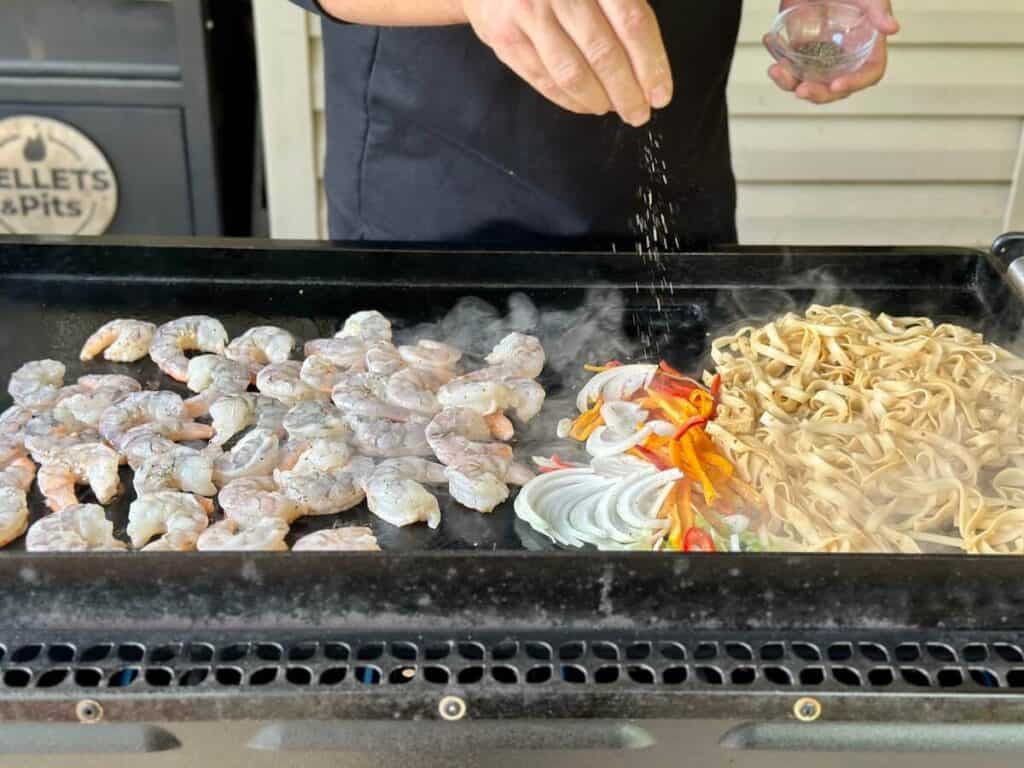 cooking shrimp and noodles on a griddle