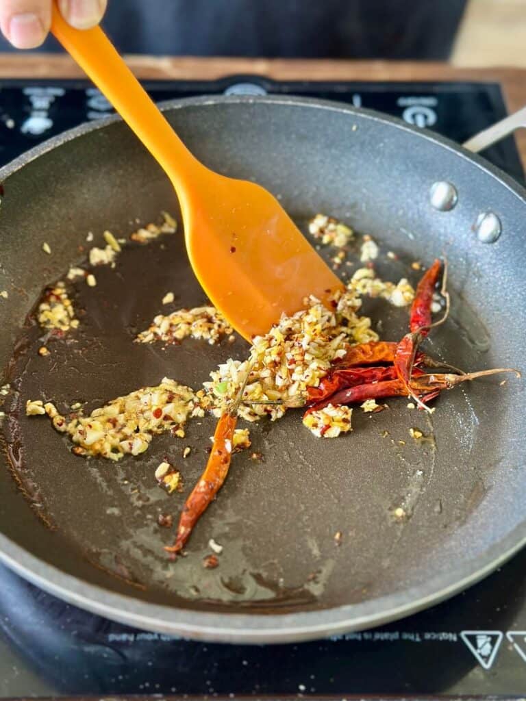 sautéing minced garlic and ginger in a skillet with chile peppers