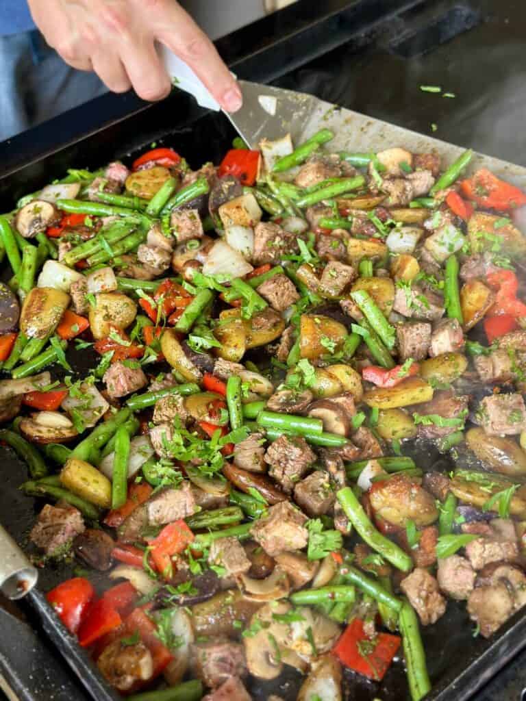 cooking steak and vegetable stir fry on a griddle